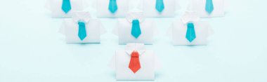 panoramic shot of origami white shirts with blue ties with one red on blue background, leadership concept clipart