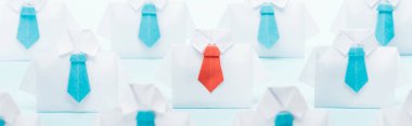 panoramic shot of origami white shirts with blue ties with one red on blue background, think different concept clipart