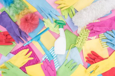 top view of messy scattered multicolored cleaning supplies on pink background clipart