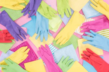 top view of messy scattered multicolored rags and rubber gloves on pink background clipart