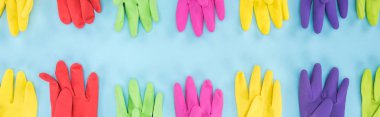 panoramic shot of multicolored rubber gloves on blue background clipart