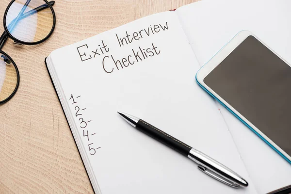 Notebook Exit Interview Checklist Lettering Numbers Wooden Table Smartphone Pen — Stock Photo, Image