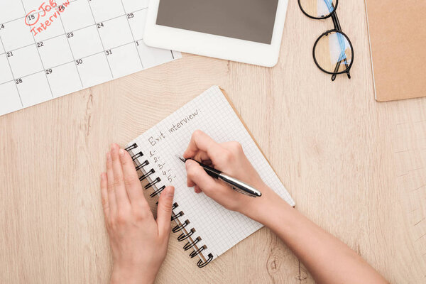 cropped view of recruiter writing in notebook with exit interview lettering