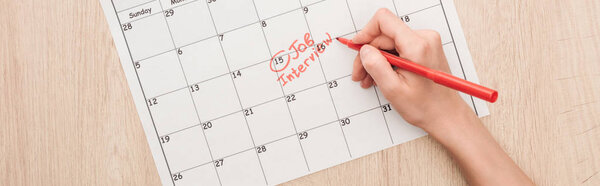 panoramic shot of recruiter writing with red marker on print calendar with job interview lettering