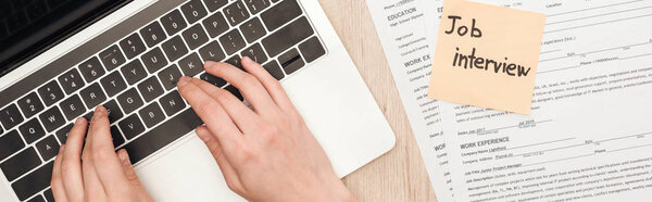 панорамный снимок вербовщика, печатающего на клавиатуре ноутбука рядом с шаблонами резюме и липкой запиской с надписью собеседования
 