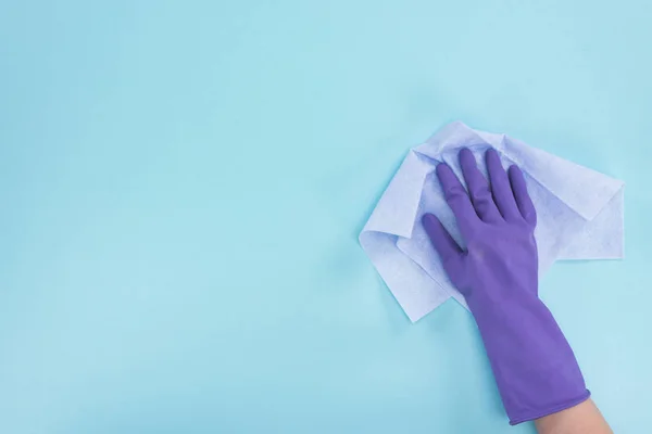 青い背景にぼろを保持する紫色のゴム手袋のクリーナーのトリミングビュー — ストック写真