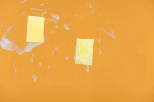 Gele Sponzen Met Schuim Oranje Achtergrond — Stockfoto