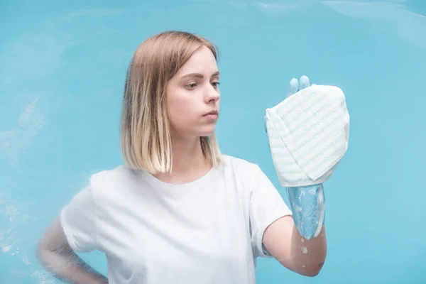 Jonge Vrouw Rubber Handschoen Schoonmaken Glas Met Doek Blauwe Achtergrond — Stockfoto