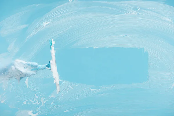 青い背景にスクイージとゴム手袋クリーニングガラスの女性のトリミングビュー — ストック写真