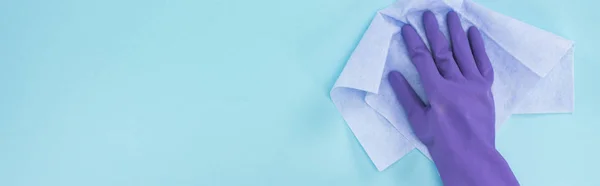 青い背景にぼろを保持する紫色のゴム手袋でクリーナーのパノラマショット — ストック写真