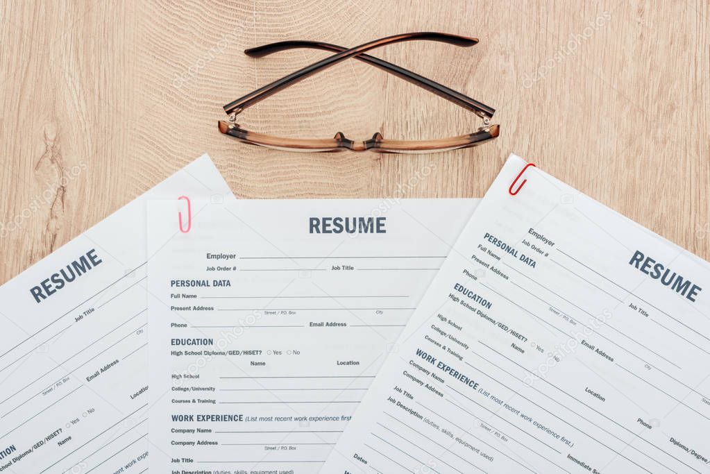 top view of print resume templates and glasses on wooden surface