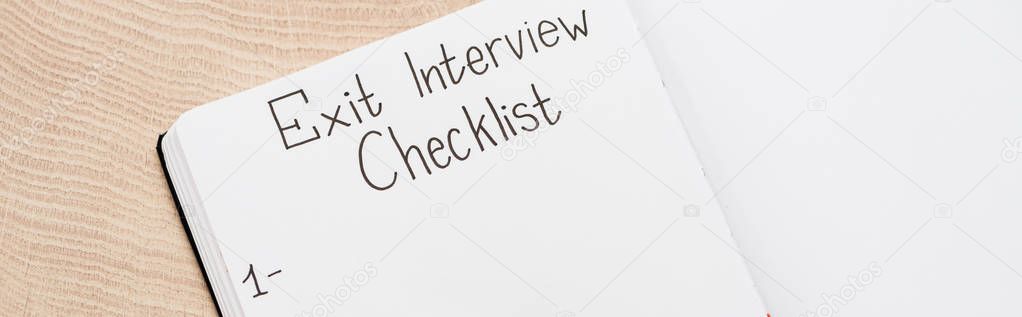 panoramic shot of notebook with exit interview checklist lettering and number on wooden table 