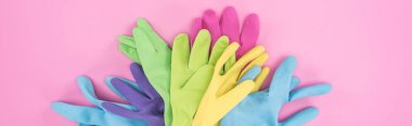 panoramic shot of multicolored rubber gloves in pile on pink background clipart