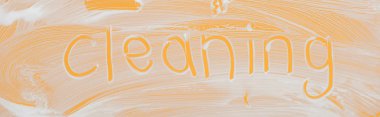 panoramic shot of glass covered with white foam on orange background with cleaning lettering clipart