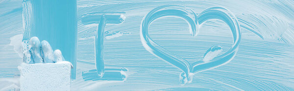 panoramic shot of cleaner with sponge near i love lettering on glass with white foam on blue background