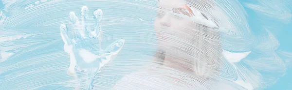 青い背景に泡で覆われたガラスに触れるゴム手袋の若い女性のパノラマショット — ストック写真