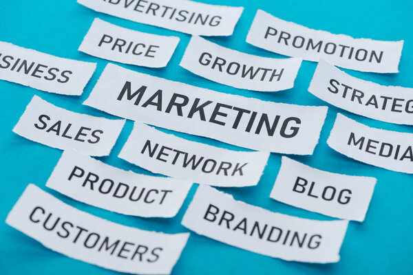 components of marketing on pieces of paper on blue 
