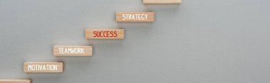 panoramic shot of wooden blocks with motivation, teamwork, success, strategy words on grey background, business concept clipart