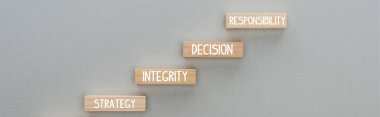 panoramic shot of wooden blocks with strategy, integrity, decision, responsibility words on grey background, business concept clipart