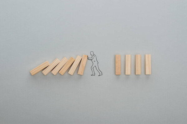 top view of drawn man pushing wooden blocks on grey background, business concept