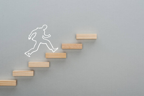 top view of drawn man running on wooden blocks symbolizing career ladder on grey background, business concept