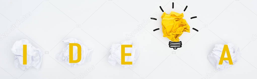 panoramic shot of crumpled paper balls, idea word and light bulb illustration on white background, business concept