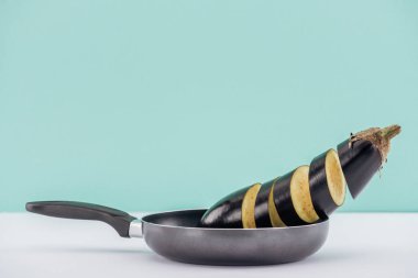Turkuaz üzerine izole beyaz masada tavada taze lezzetli dilimlenmiş patlıcan