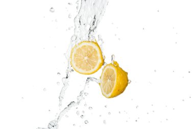 Sarı kesim limonlar berrak su sıçratır ve beyaza düşer.