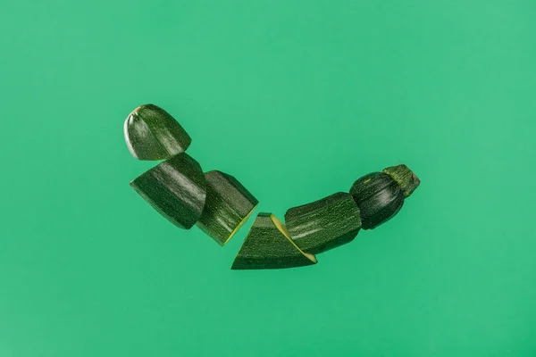 Freshly sliced organic green zucchini isolated on green
