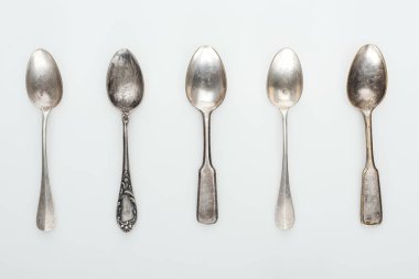 top view of shiny aged silver empty spoons in row on white background clipart