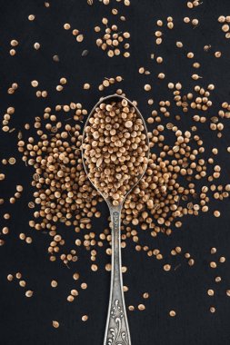 top view of Coriander in silver spoon on black background clipart