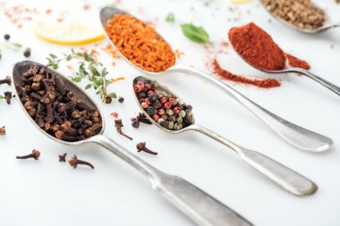 close up view of colorful indian spices in silver spoons on white background clipart