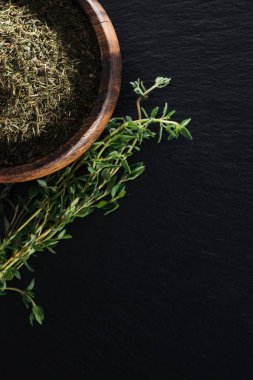 siyah arka plan üzerinde yeşil bitki yakın ahşap kase kurutulmuş kekik üst görünümü