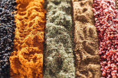 close up view of various aromatic traditional indian spices in rows clipart