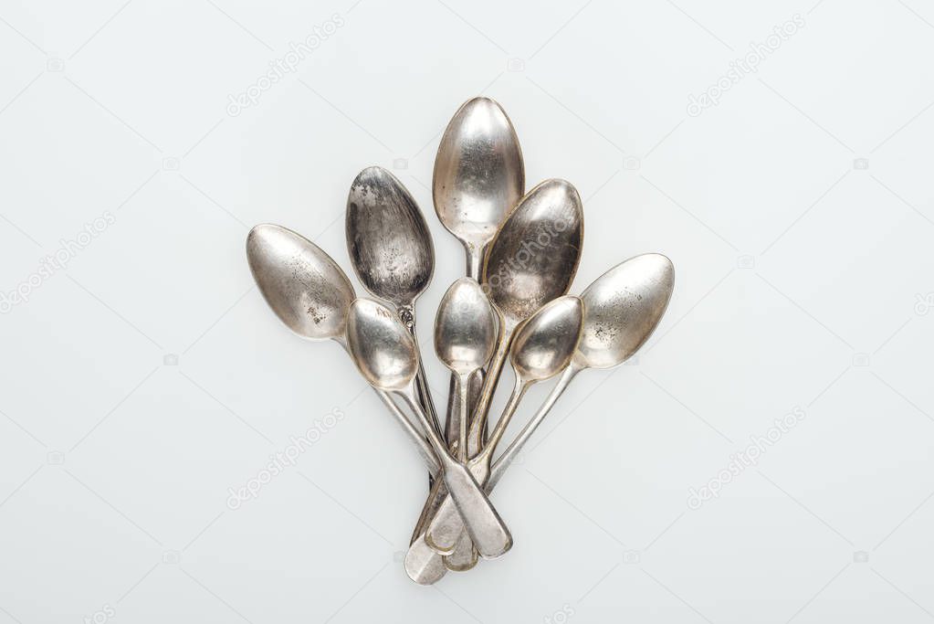 top view of shiny old silver empty spoons on white background