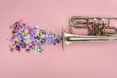 colorful confetti with trumpet on pink background clipart