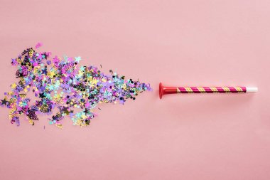 Party horn and multicolored confetti on pink background clipart