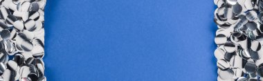 Mavi arka plan üzerinde gümüş konfeti çerçeve panoramik çekim 