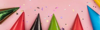 Panoramic shot of multicolored party hats on pink  festive background clipart