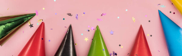 Panoramic shot of multicolored party hats on pink  festive background