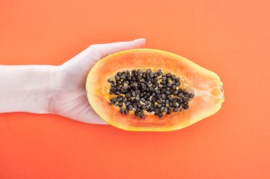 turuncu izole siyah tohumlar ile olgun egzotik papaya yarısı tutan kadın kırpılmış görünümü