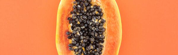 panoramic shot of ripe exotic papaya half with black seeds isolated on orange with copy space