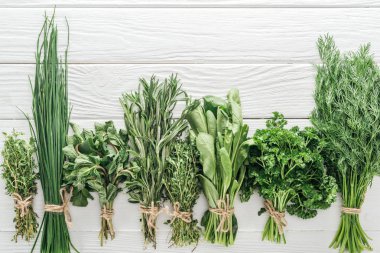 top view of various green herbs on white wooden table clipart