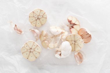 top view of cut garlic cloves on white paper background clipart