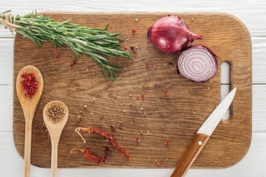 top view of various spices and rosemary near knife on wooden chopping board clipart