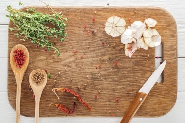 top view of various spices and thyme on wooden chopping board clipart