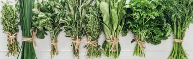 top view of various green herbs on white wooden table, panoramic shot clipart