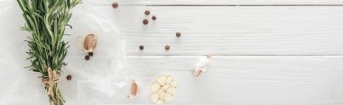 panoramic shot of garlic cloves, black pepper and rosemary on white wooden table clipart
