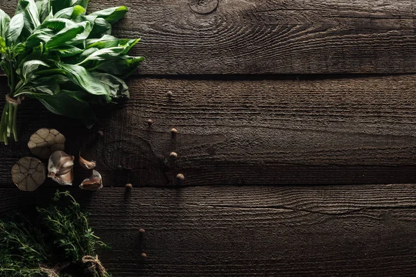 在木制风化餐桌上 靠近黑胡椒和大蒜丁香的绿色百里香和罗勒的顶视图 — 图库照片