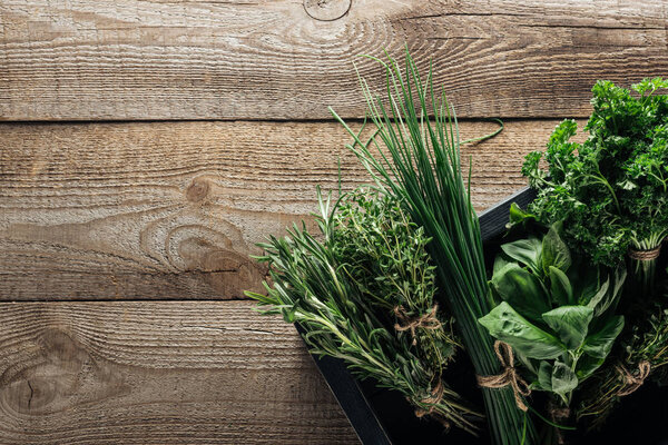 top view of green thyme, spinach, parsley, rosemary and green onion in box on wooden weathered table with copy space